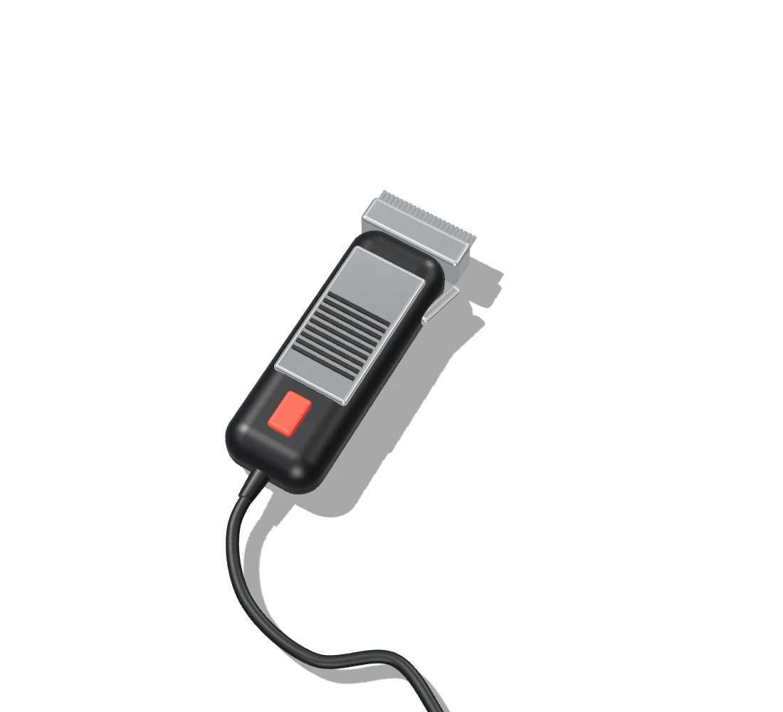 A black hair clipper with a steel blade and a red power switch, lying in hard light.